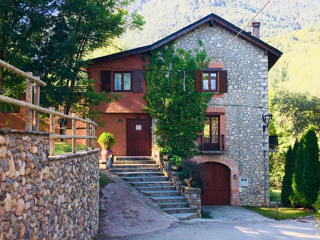 ein Haus mit einer Steinmauer und einer Treppe davor in der Unterkunft Casa El Molí de Bor a Cerdanya in Bor