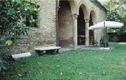 a brick building with a bench and an umbrella at Antica Corte Hotel Residence di Charme Ferrara in Ferrara