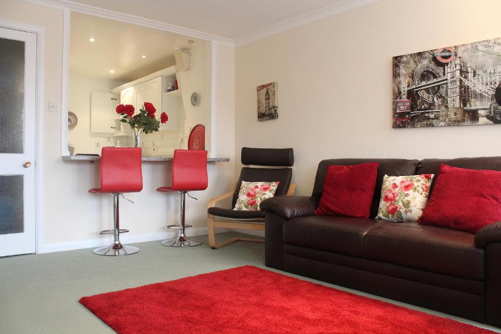 a living room with a brown couch and red pillows at Cossack Holiday Home in Winchester