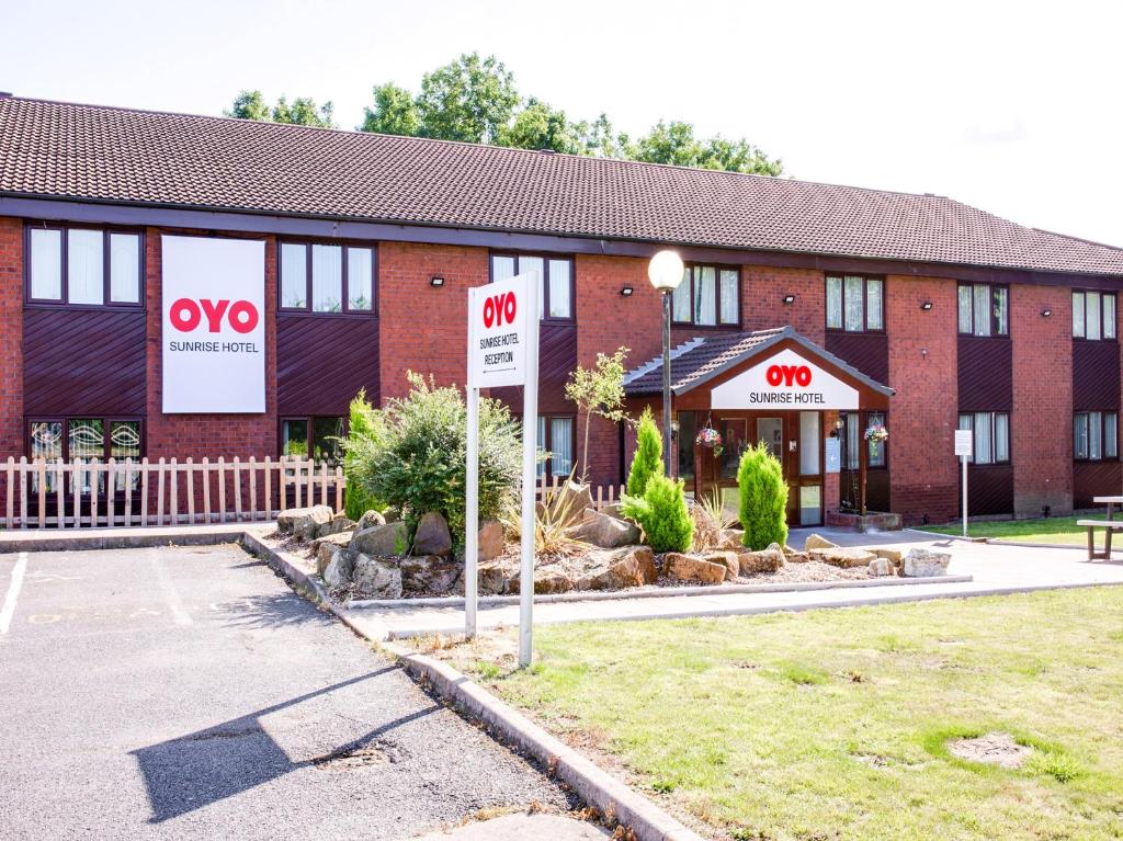 un edificio de ladrillo rojo con señales de aww delante de él en OYO Sunrise Hotel, A46 N Leicester, en Thrussington