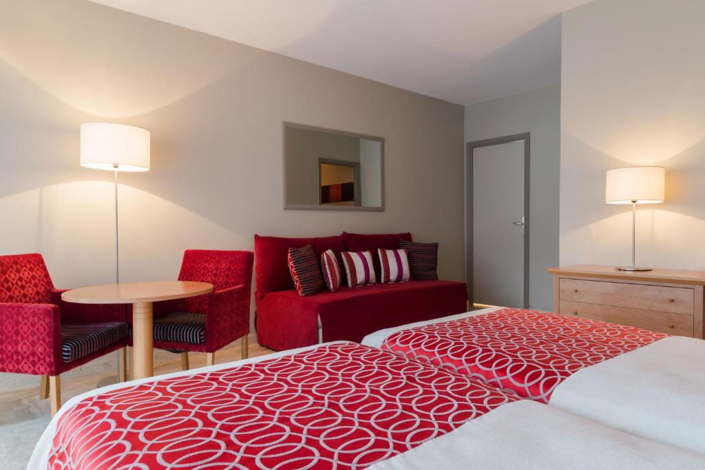 a bedroom with a red bed and two red chairs at The Originals Boutique, Hôtel Les Strélitzias in Juan-les-Pins