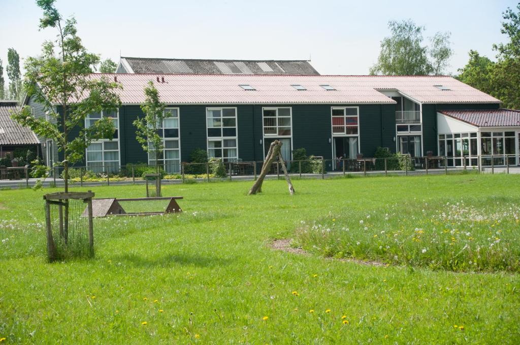 um edifício com um pátio verde com um parque infantil em Newhouse Logies em Zevenhoven