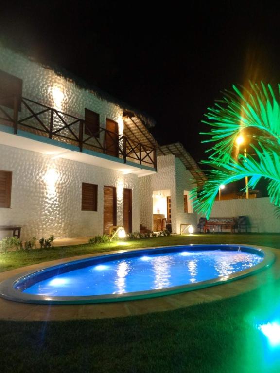 a swimming pool in front of a house at night at Pousada Angels in Barra Grande