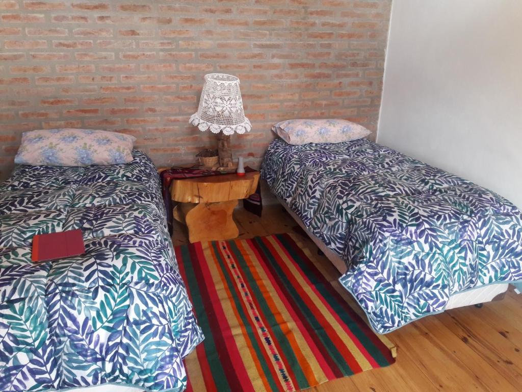 Habitación con 2 camas y mesa con lámpara. en Cabañas Vientos del Sur en Villa Yacanto