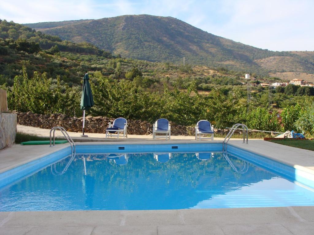 a pool with chairs and a mountain in the background at Casas Rurales Manolo in Casas del Monte