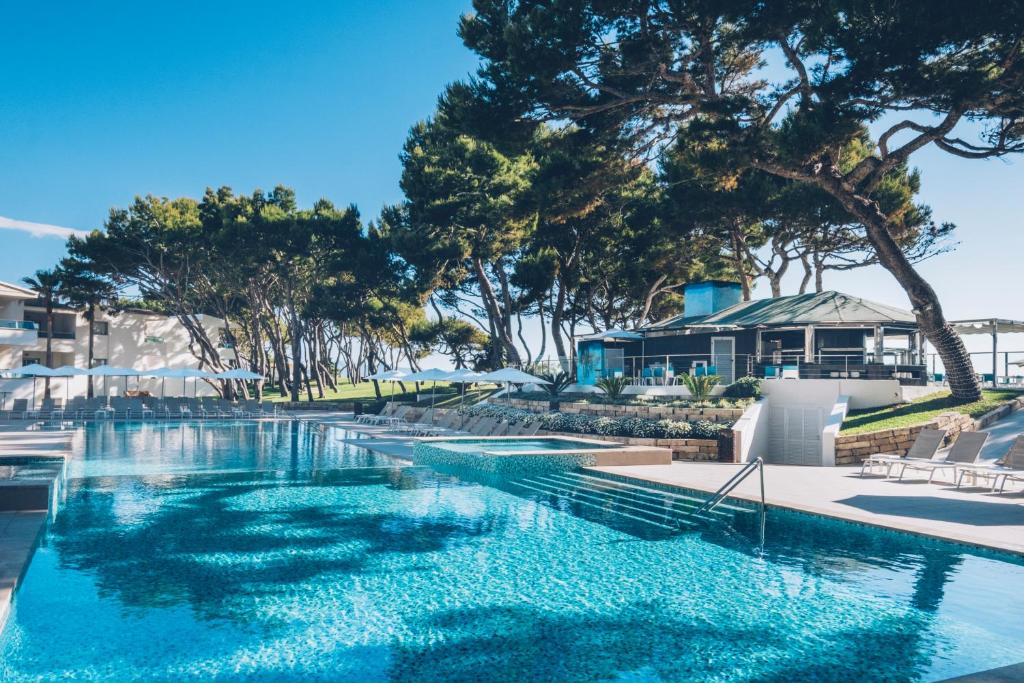a swimming pool with blue water in a resort at Iberostar Selection Playa de Muro Village in Playa de Muro