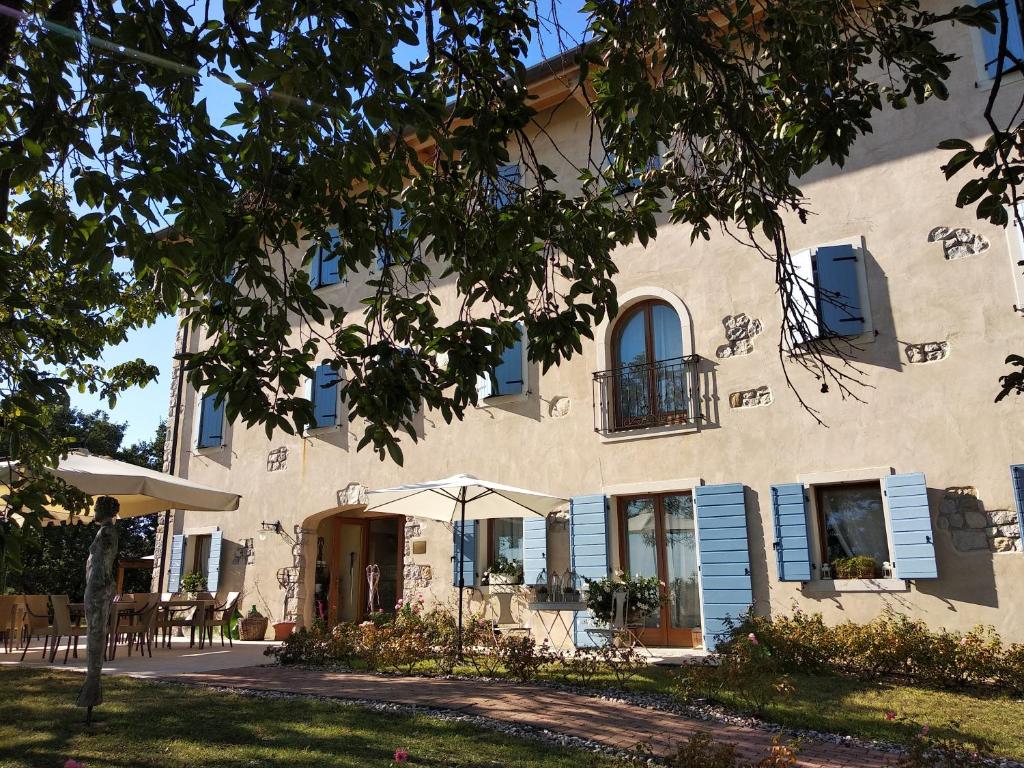 a large white building with blue shutters at Alice Relais Nelle Vigne in Vittorio Veneto