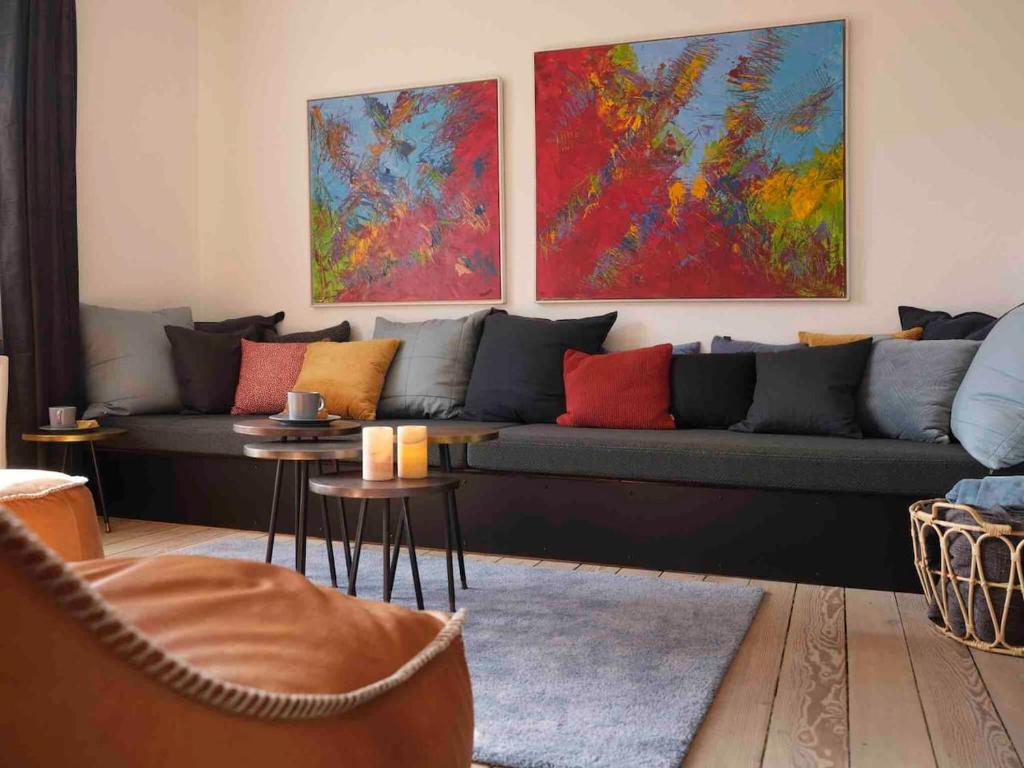 a living room with a couch and paintings on the wall at Cozy Stay in Aarhus