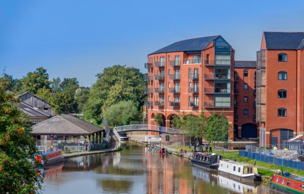 a river in a city with buildings and boats on it at City Centre Chester Waterways Apartment in Chester