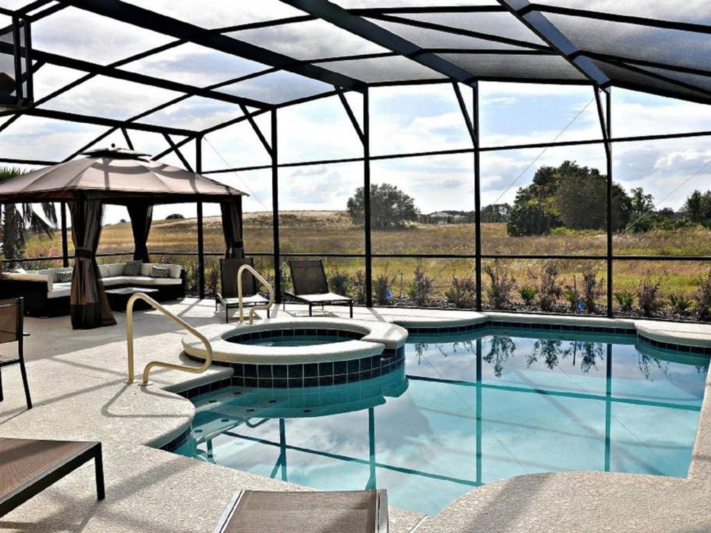 a swimming pool with an umbrella and a patio at 5356 Water Park Solterra Resort 5bed house - 10 minutes from Disney in Davenport