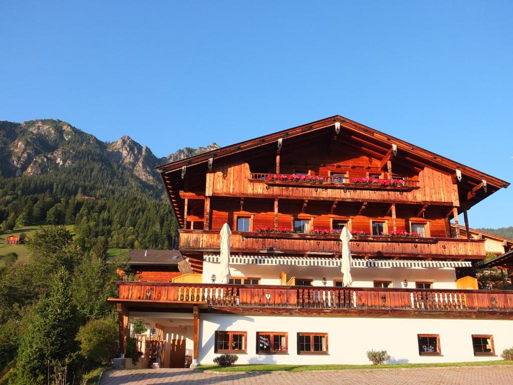 a large wooden building with a balcony in the mountains at Apartment Haus Dahoam in Alpbach