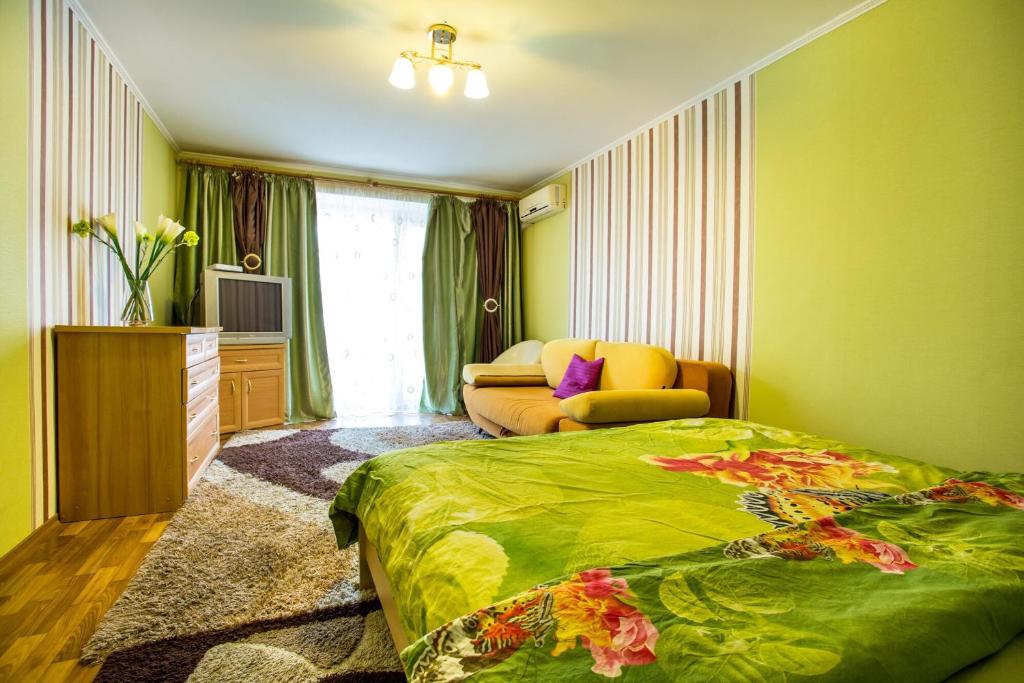 1 dormitorio con 1 cama, 1 silla y TV en Квартира на Соборной, en Mykolaiv