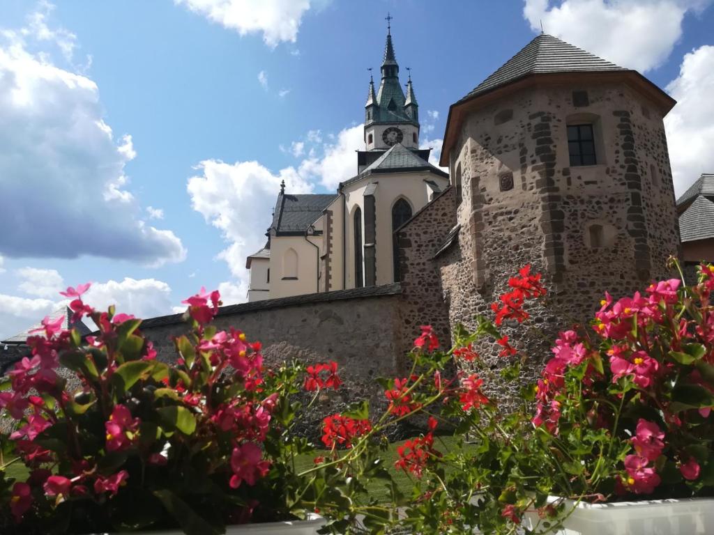 Uma velha igreja com flores cor-de-rosa à frente. em Pod Zámkom em Kremnica
