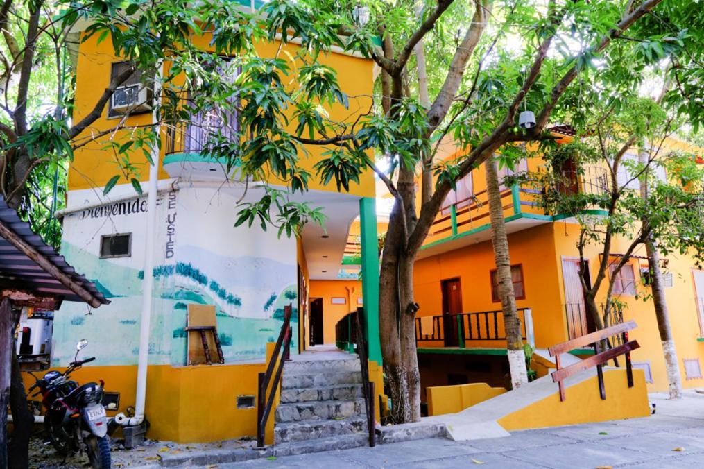 um edifício amarelo com um mural na lateral em Hotel Posada Playa Manzanillo em Puerto Escondido