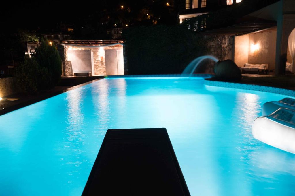 basen w nocy z niebieskim oświetleniem w obiekcie Tranquil Infinity Pool Getaway (private jacuzzi and steam bath, pool, garden, sea and city views) w mieście Wolos