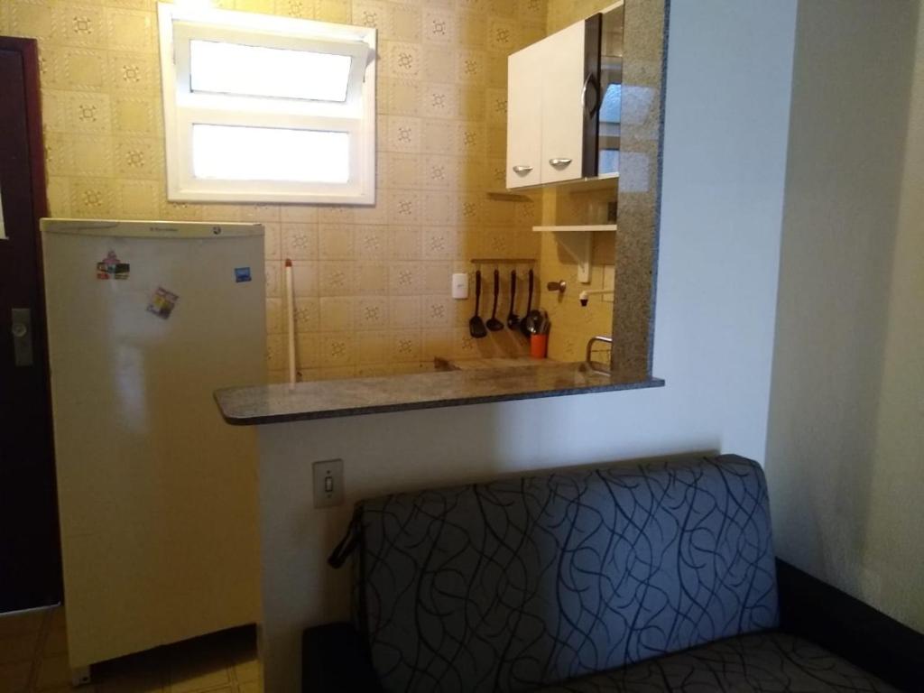eine kleine Küche mit einem Kühlschrank und einem Fenster in der Unterkunft 1 quarto 2 camas de solteiro in Guarapari