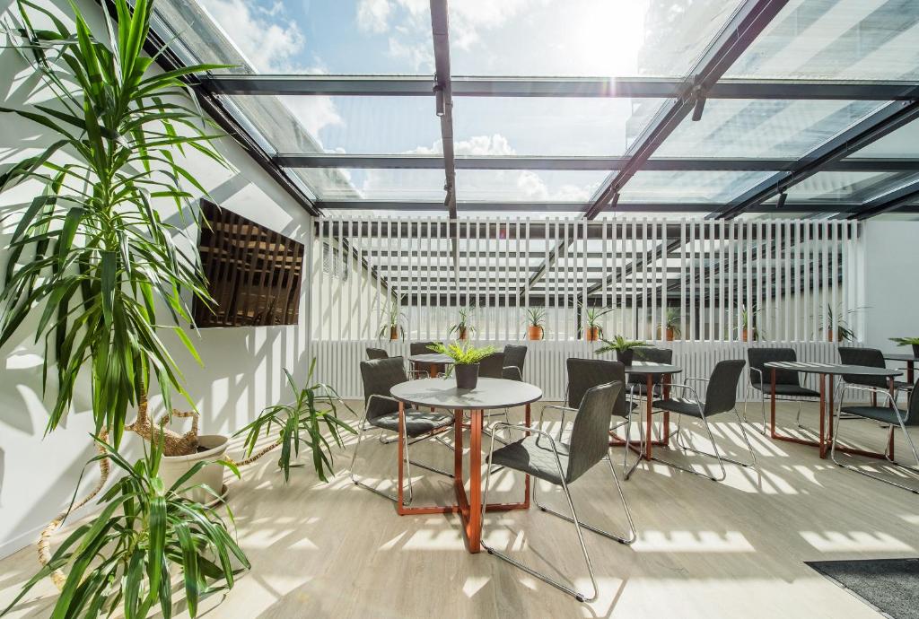 einen Wintergarten mit Tischen, Stühlen und Pflanzen in der Unterkunft Zaliakalnio terasos apartamentai in Kaunas
