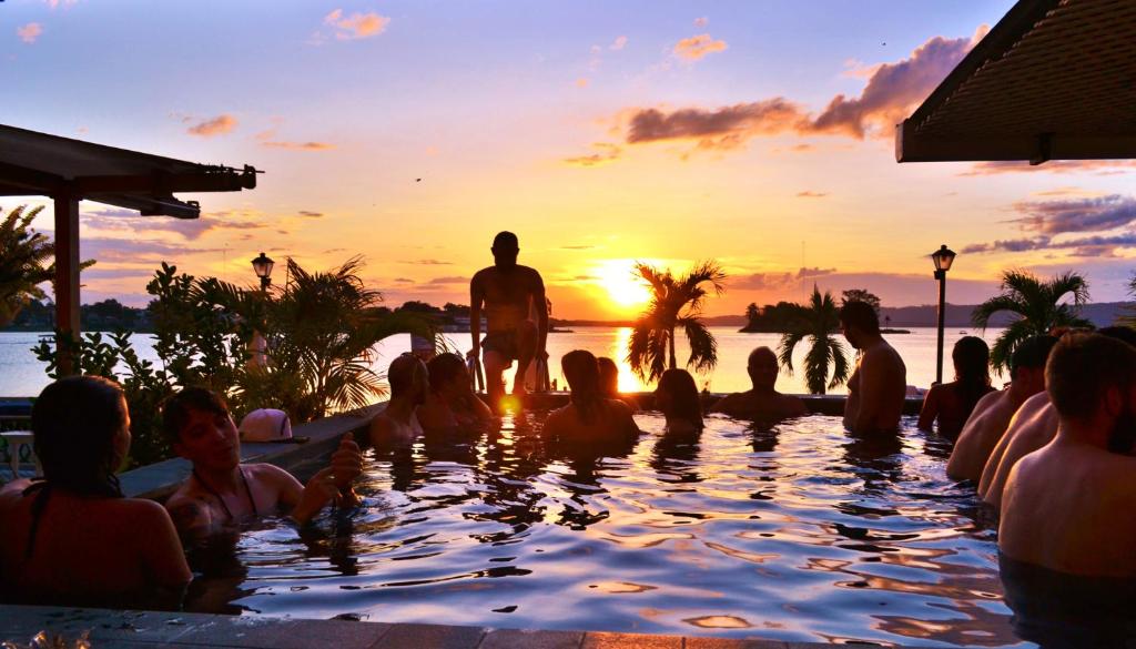 een groep mensen die in een zwembad zitten te kijken naar de zonsondergang bij Hotel Petén Express in Flores