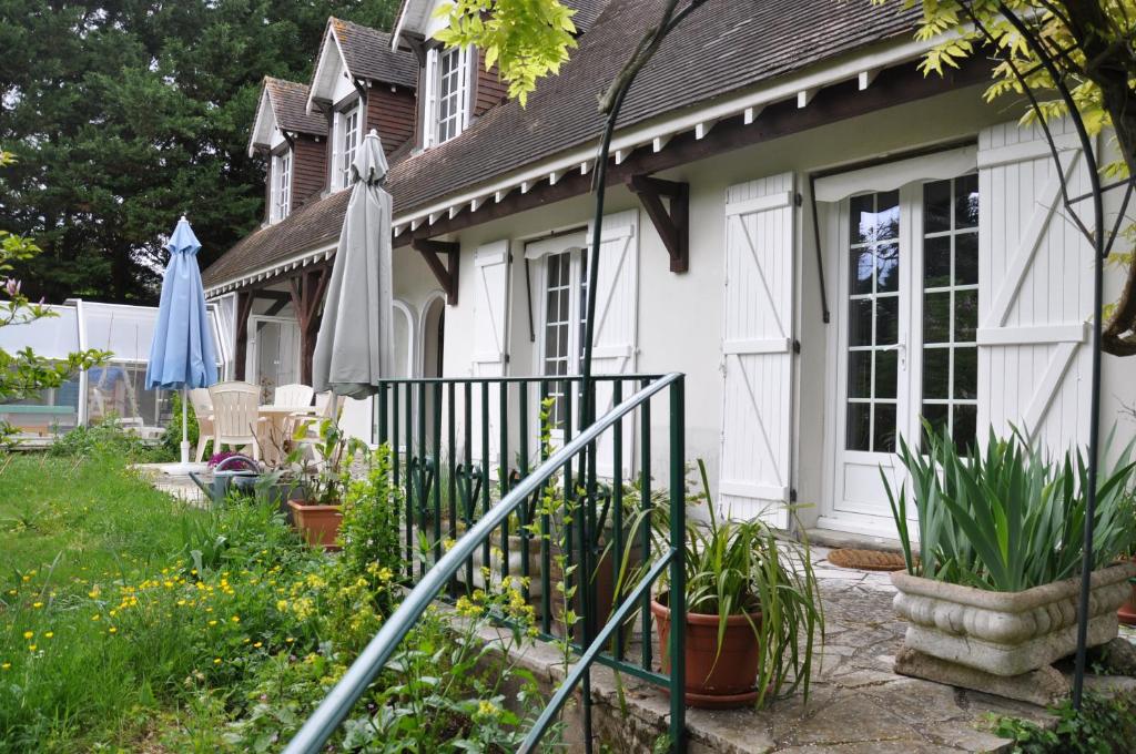 una casa blanca con un paraguas y algunas plantas en Chez Cyril et Vi, en Saint-Règle