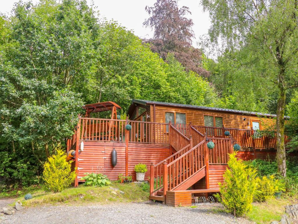 a log cabin with a large deck in the woods at Willow Lodge in Windermere
