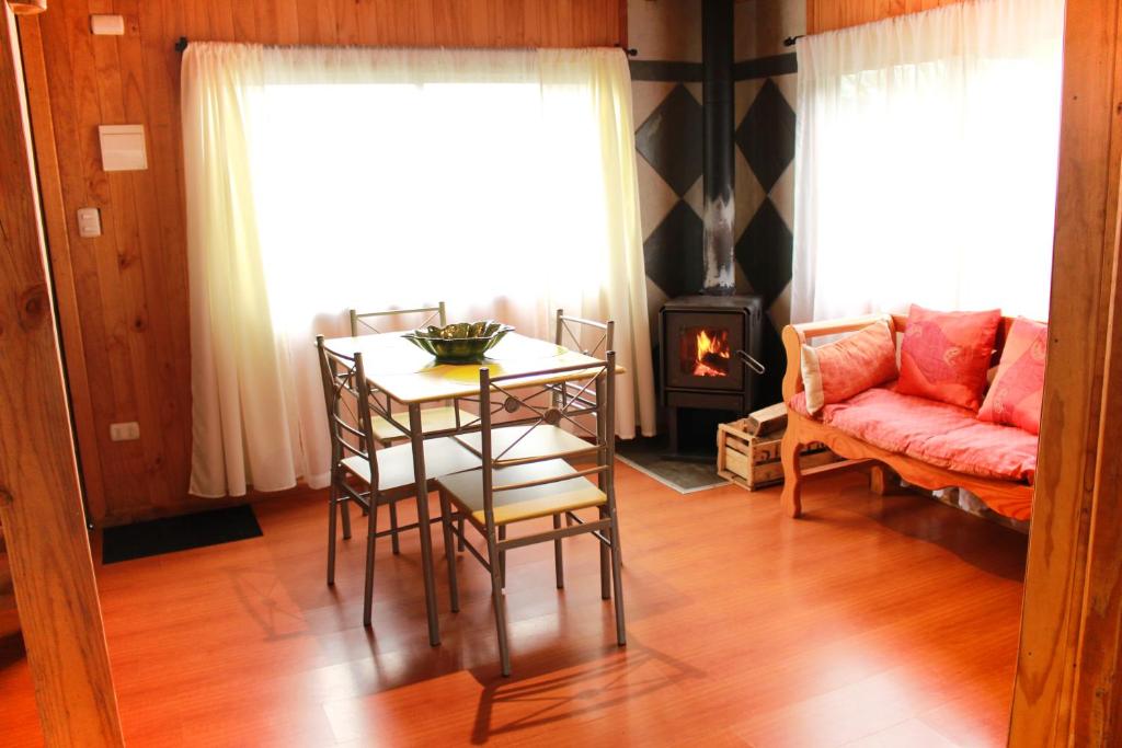 een woonkamer met een tafel, een bank en een open haard bij Cabanas L'ESCALE in Coñaripe