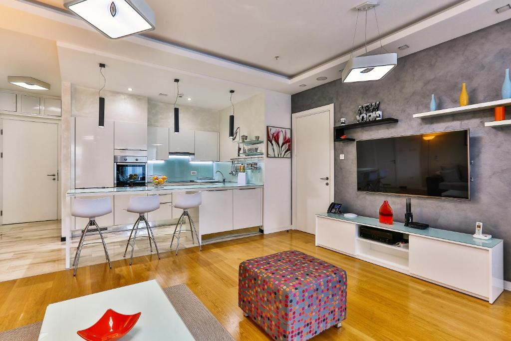 a large kitchen with white cabinets and a bar with stools at DeLux and Urban apartments Hotel Tre Canne Budva in Budva