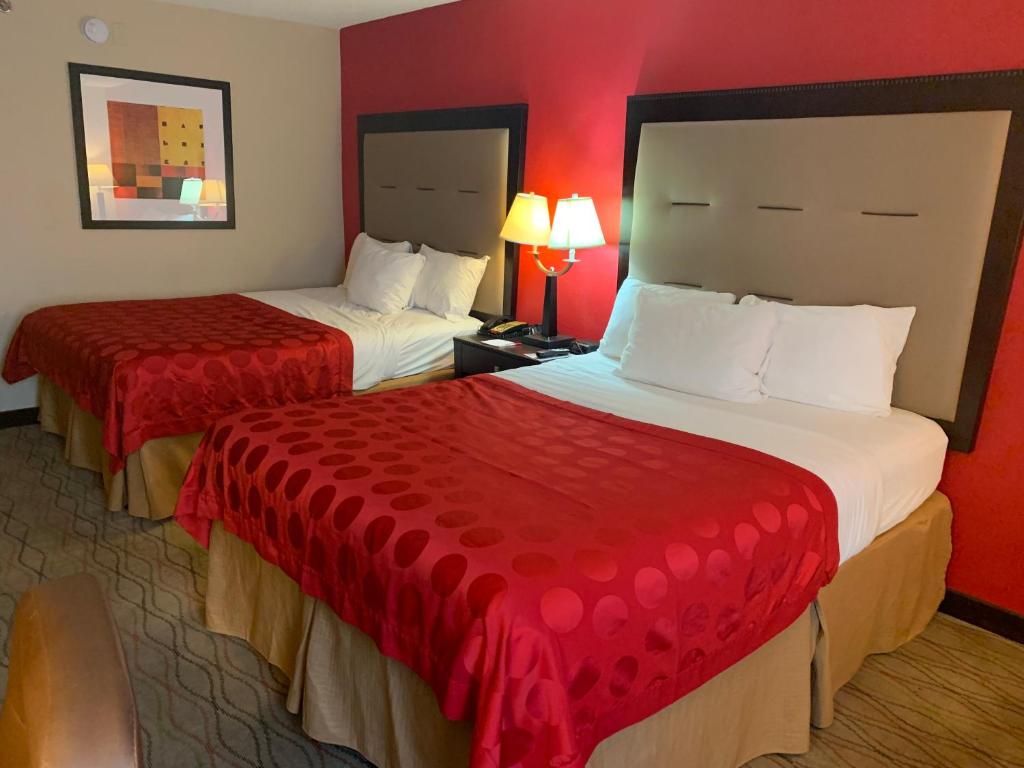 2 Betten in einem Hotelzimmer mit roten Wänden in der Unterkunft Ramada by Wyndham Gainesville in Gainesville