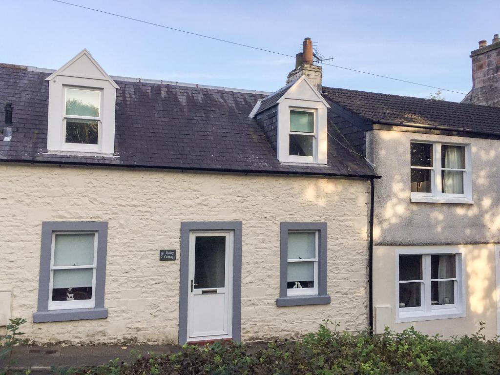 a white house with white windows and a black roof at Daisy Cottage in Moffat
