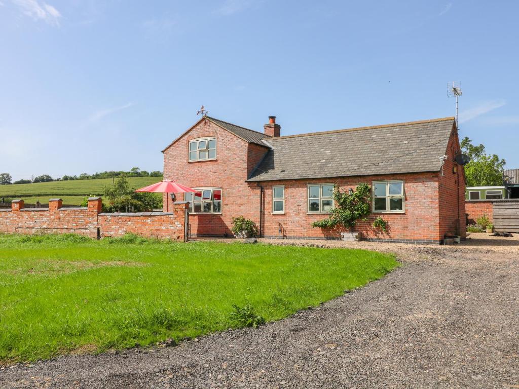 a brick house with a grass field in front of it at Grooms Cottage in Leicester