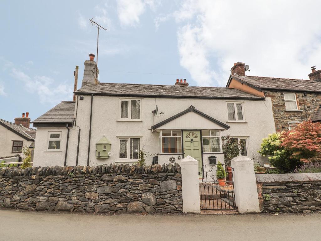 ein weißes Haus mit einem Steinzaun davor in der Unterkunft Dove Cottage in Abergele