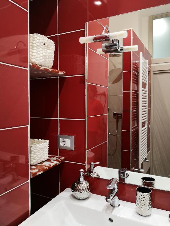 Łazienka z czerwonymi ścianami, umywalką i lustrem w obiekcie La Canzanella Guest House w mieście Neapol
