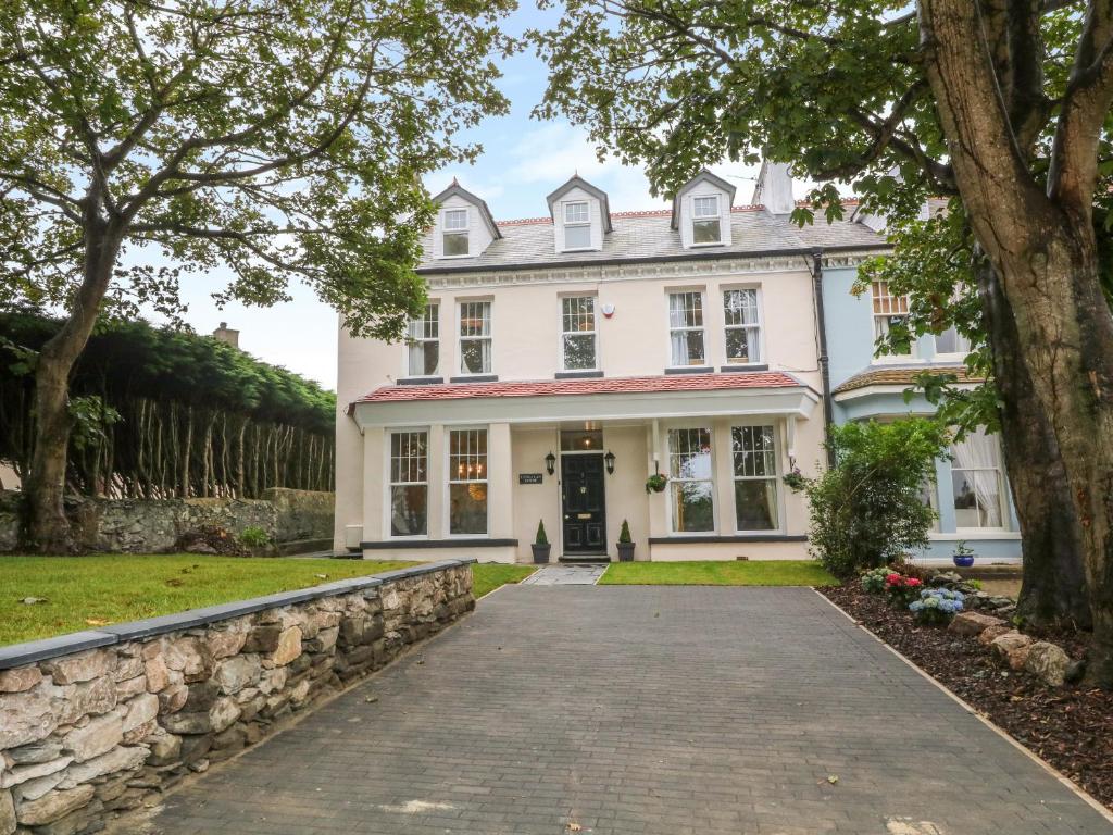 a white house with a stone wall and a driveway at Lyngaran House in Holyhead