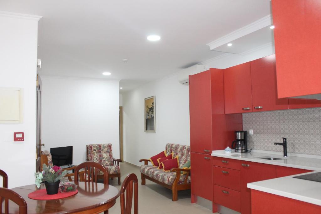 eine Küche mit roten Schränken und ein Esszimmer in der Unterkunft Apart Baía do Sado I in Setúbal