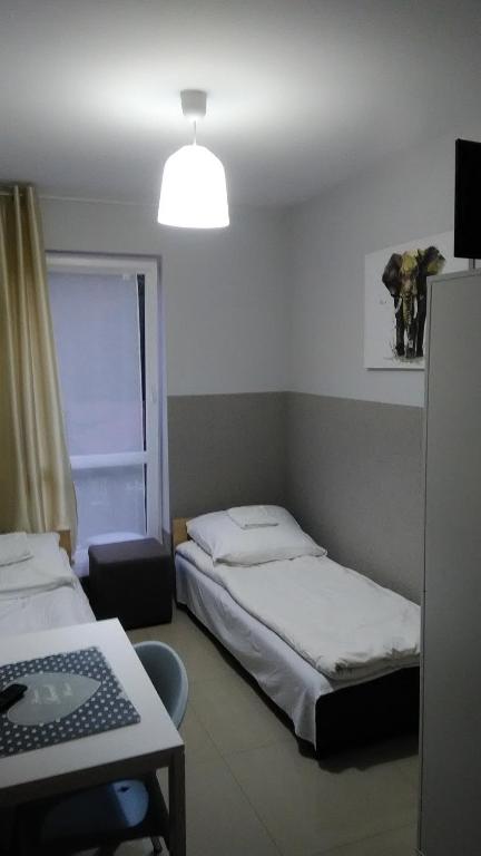 Cette chambre comprend deux lits, un bureau et une lampe. dans l'établissement Pokoje Henryk, à Korytów