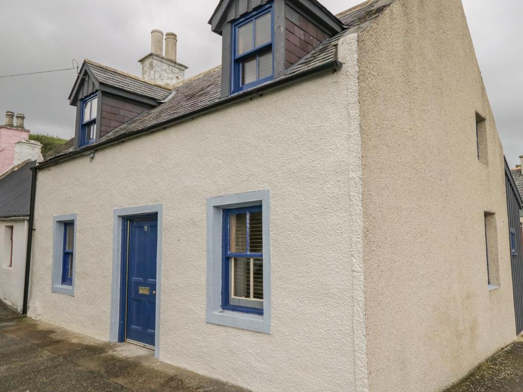 a white house with blue windows and a blue door at 11 Village in Banff