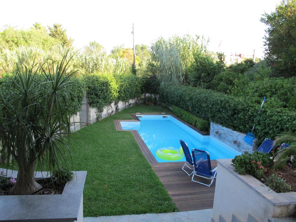 un patio trasero con una piscina con sillas y un frisbee en Villa Le Lanterne Pool & Relax, en Mondello