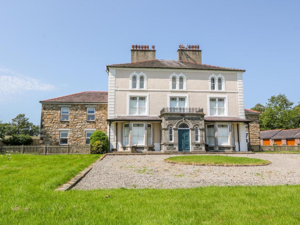 una grande casa in pietra con un ampio cortile di Tirionfa a Llangefni