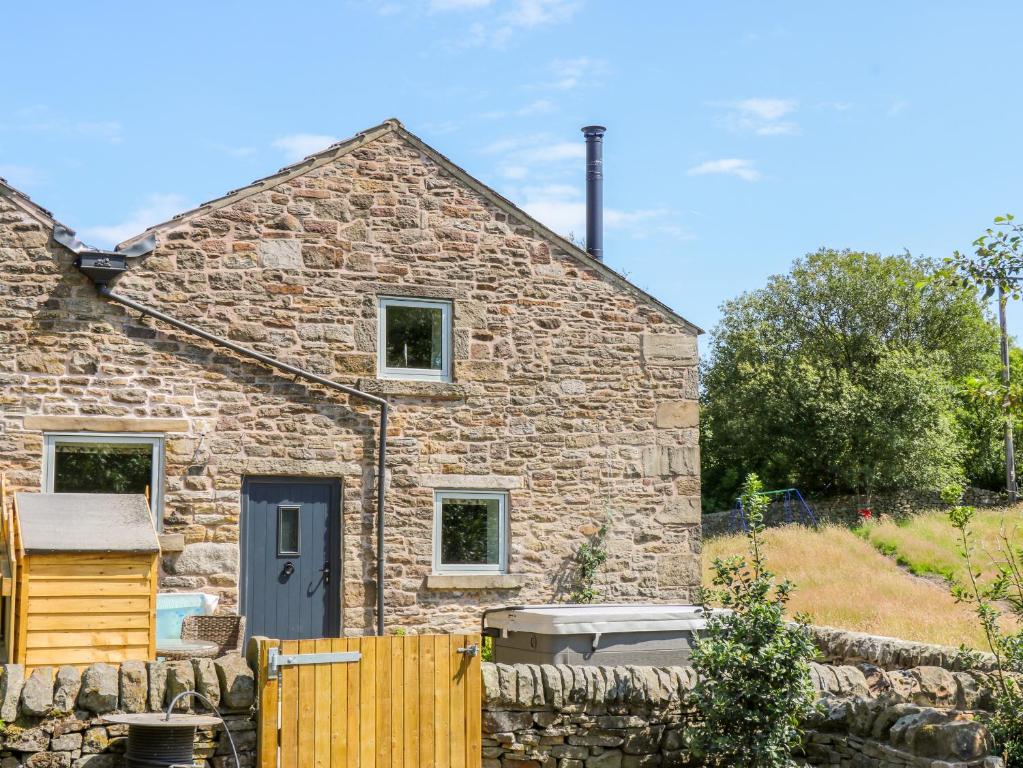 a stone cottage with a black door and a fence at Overlea Cowshed in Highpeak Junction