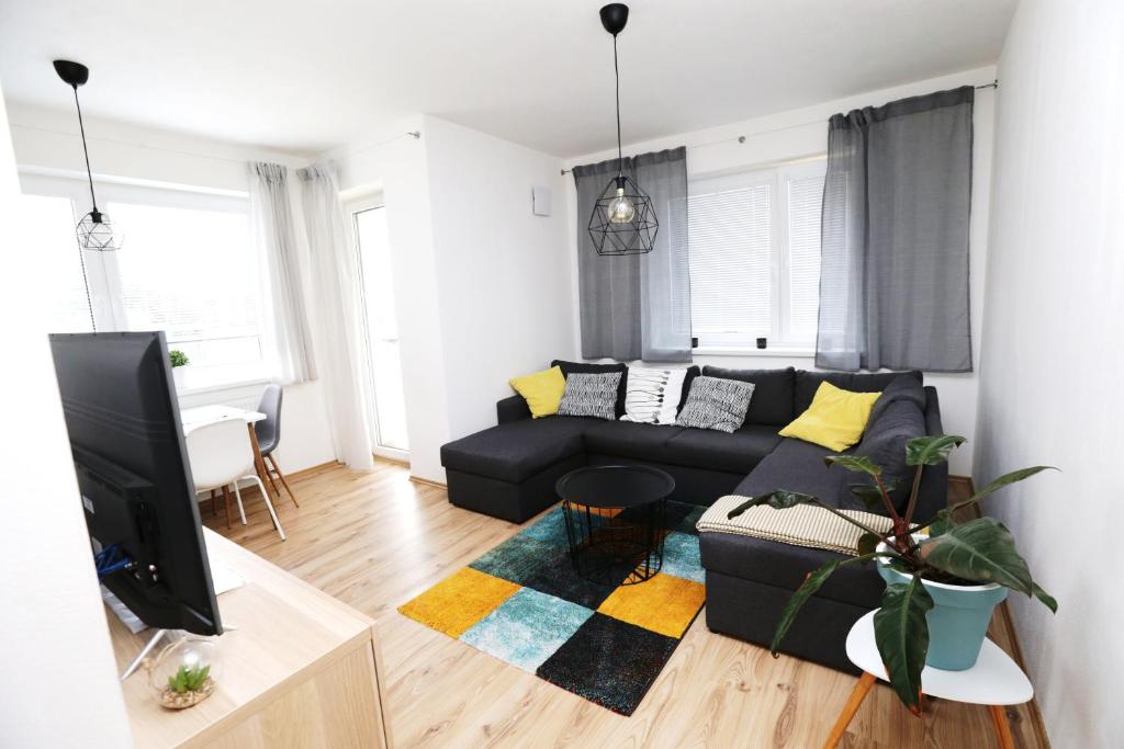 a living room with a black couch and a tv at Šamorín - apartment in the center - free parking in Šamorín