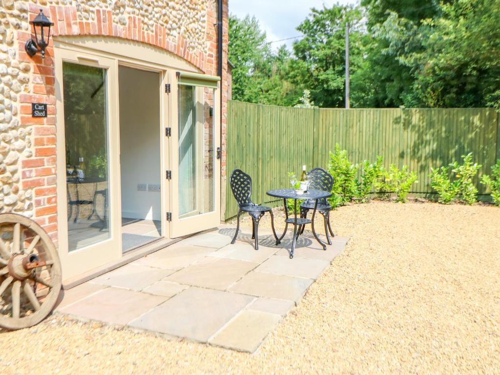 a patio with a table and chairs and a fence at The Cart Shed in East Dereham