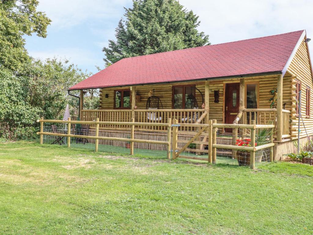 a wooden cabin with a red roof and a yard at The Retreat in Brandon