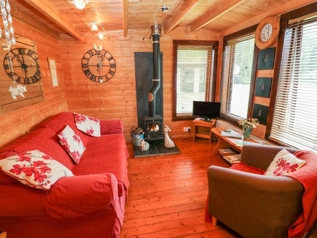 un soggiorno con divano rosso e camino di The Lodge a Milford Haven