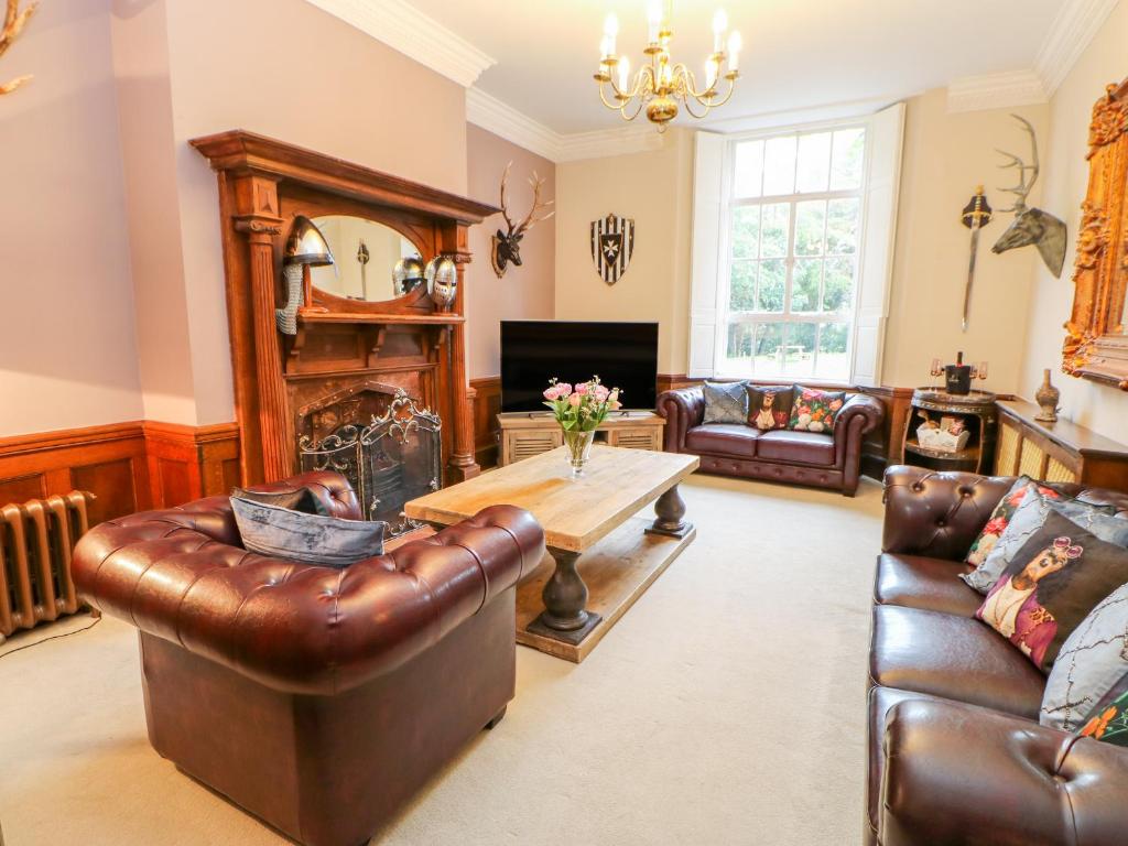 a living room with a leather couch and a table at Woodlands View Stanhope Castle in Bishop Auckland