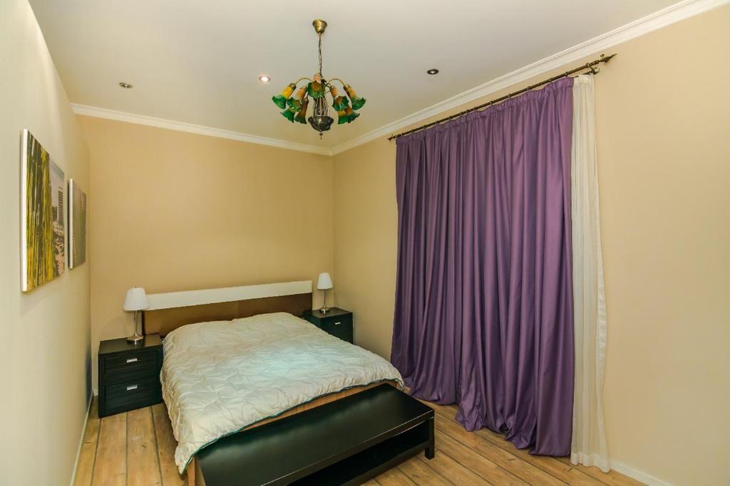een slaapkamer met een bed met paarse gordijnen en een kroonluchter bij For our friends Center 2 bedrooms in Baku