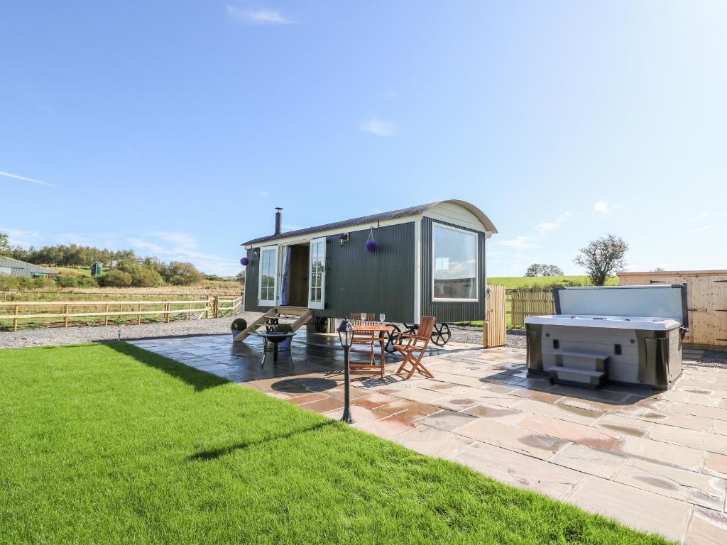 a green tiny house with a picnic table and a grill at Cwt Y Gors in Ystrad Meurig