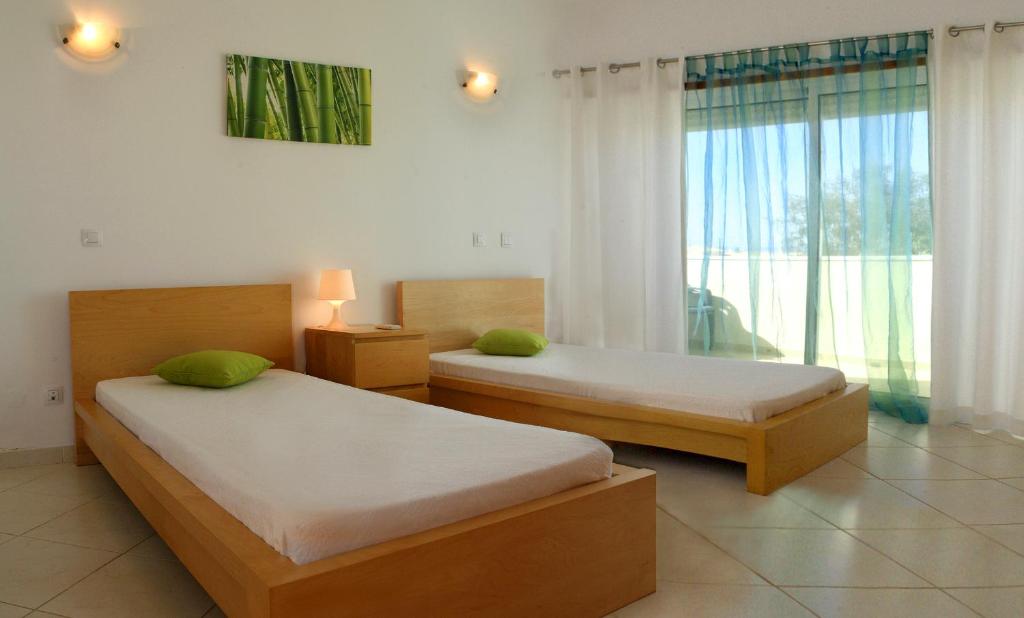 dwa łóżka w pokoju z oknem w obiekcie Villas Oceano w Albufeirze
