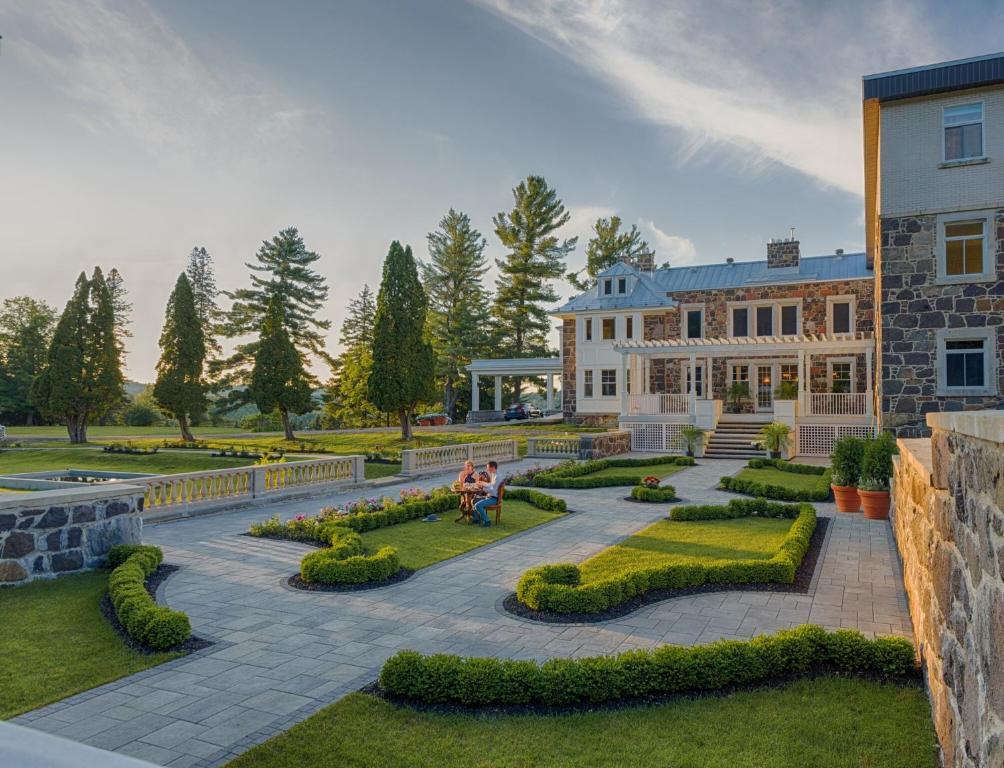 a man sitting on a bench in front of a building at StoneHaven Le Manoir - Relais & Châteaux in Sainte-Agathe-des-Monts