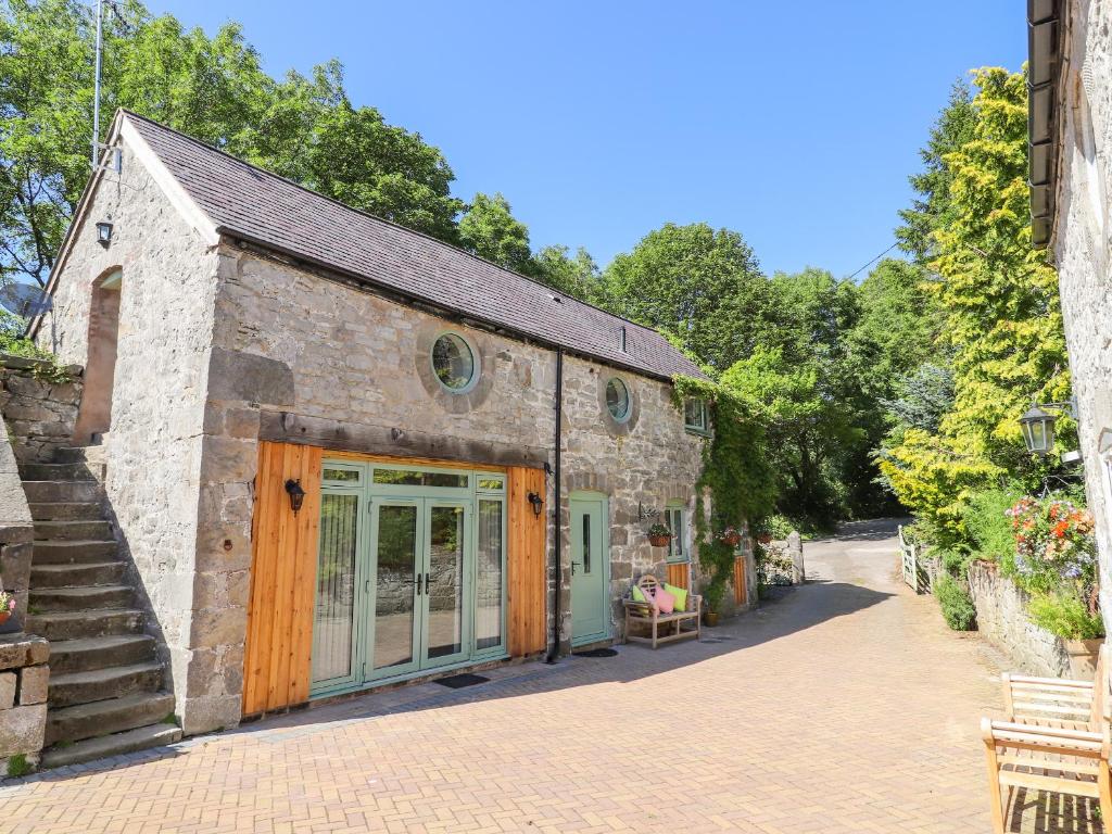 an old stone building with glass doors and stairs at The Old Coach House in Mold