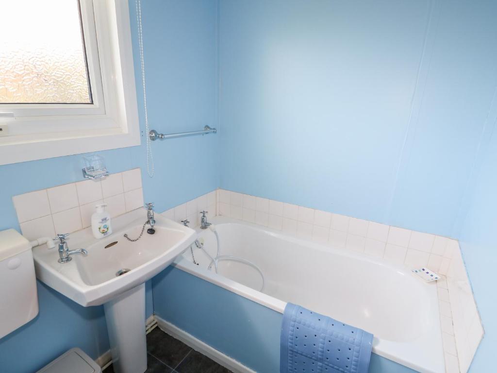 a bathroom with a white tub and a sink at Moggs Retreat in Skegness