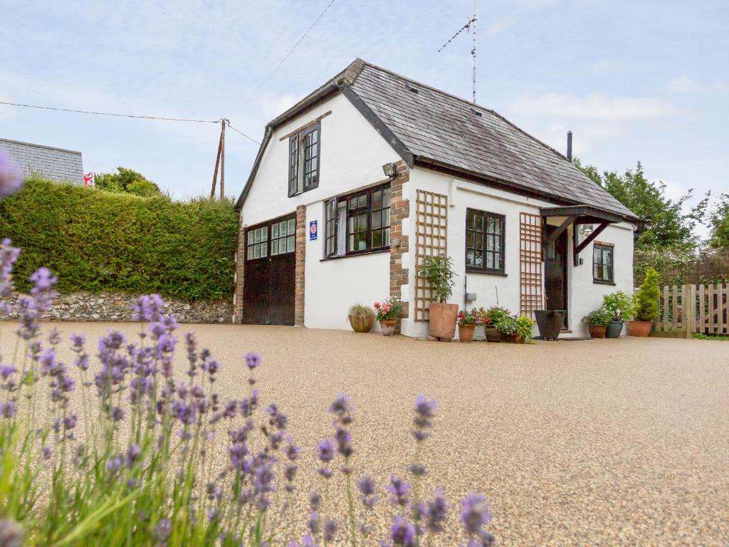 a white house with purple flowers in front of it at Little England Cottage in Milborne Saint Andrew